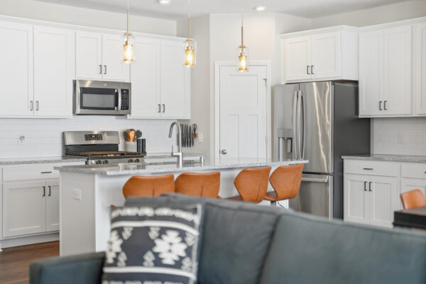 Modern kitchen interior with stainless steel appliances and bar seating, showcasing HDR photography by Corridor Media.