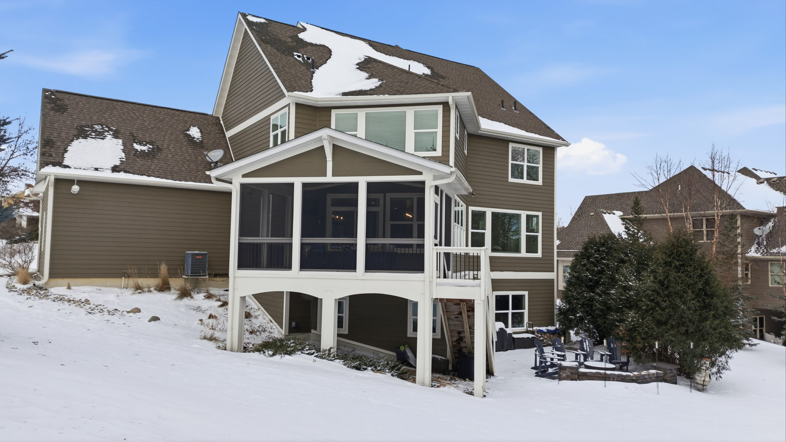 Real estate photography of a house with snow-covered roof and screened-in porch.