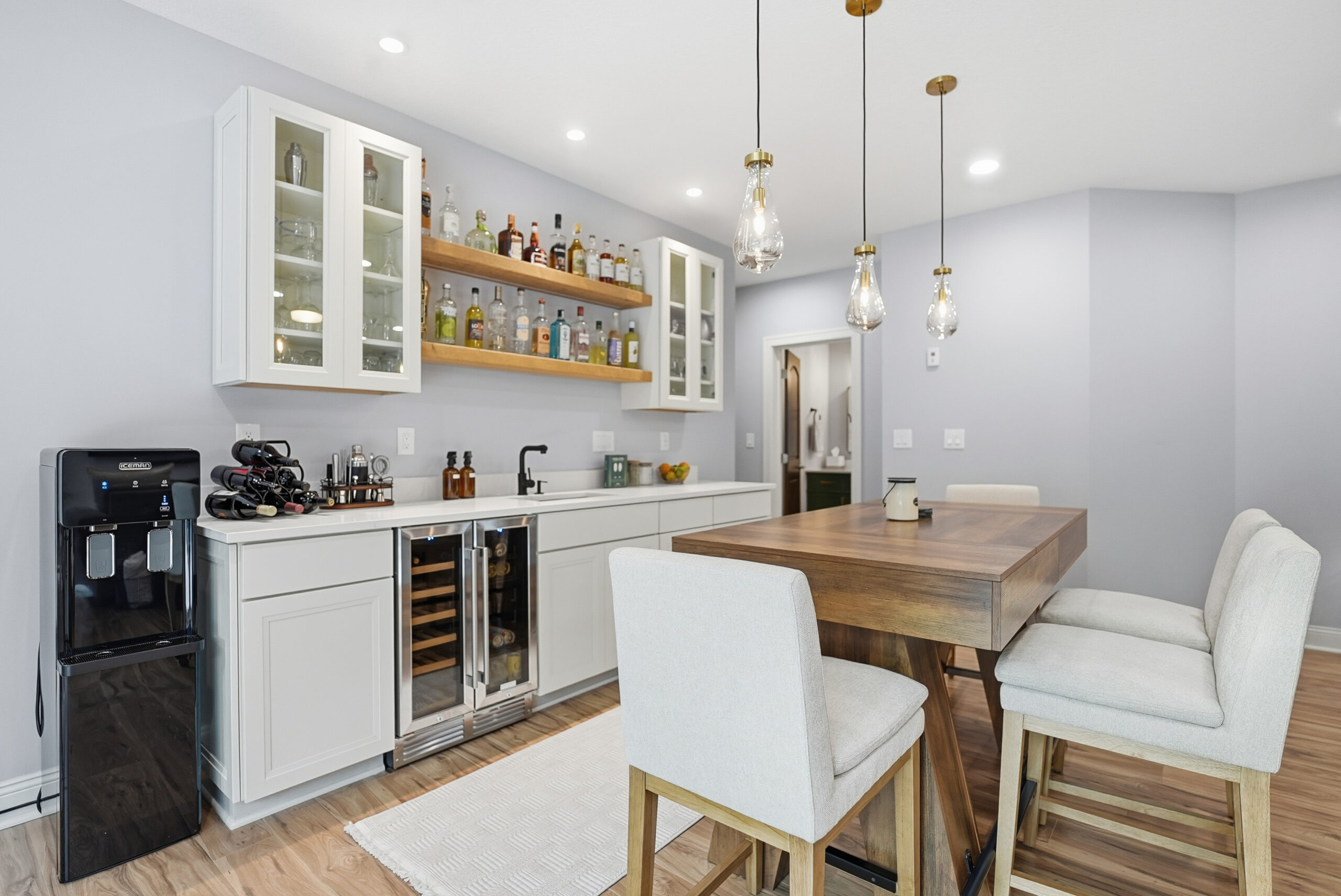 Modern home bar area with built-in cabinets, shelves, and wine fridge, showcasing real estate photography services.
