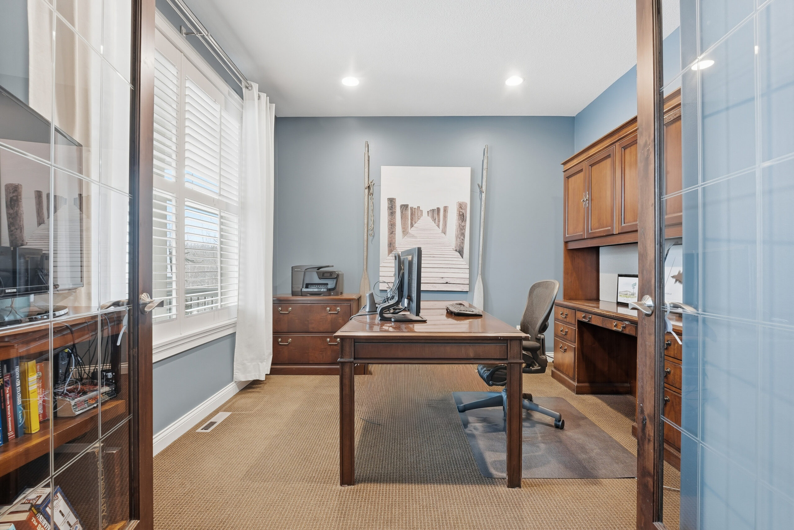 Interior real estate photography showcasing a home office with wood desk and cabinetry.