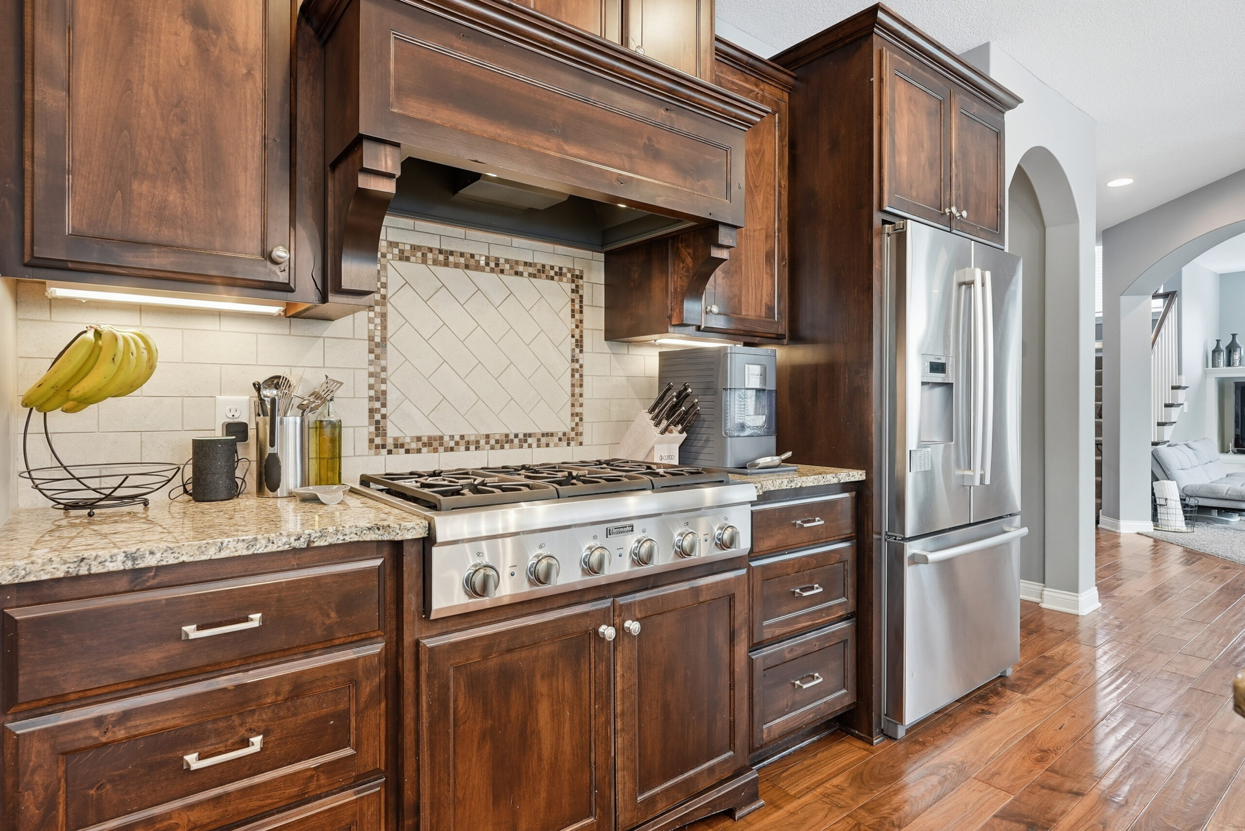 Real estate photography showcasing a modern kitchen with wood cabinetry and stainless steel appliances.