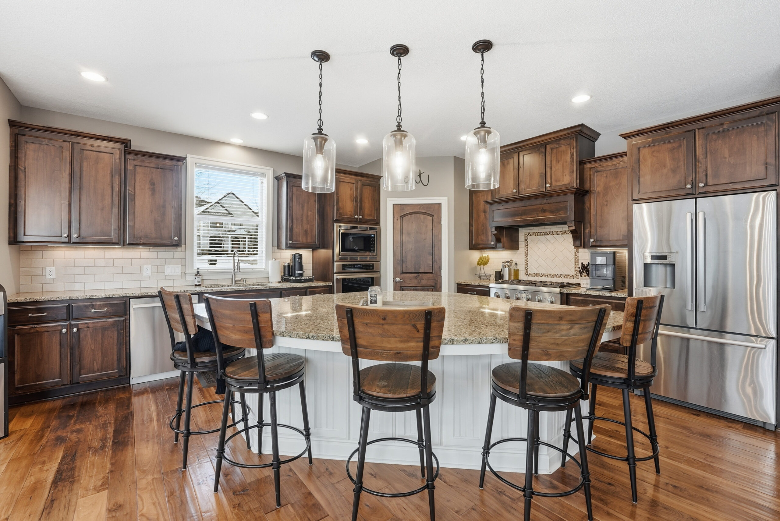 Modern kitchen interior with wood cabinetry and island seating, showcasing real estate photography services.