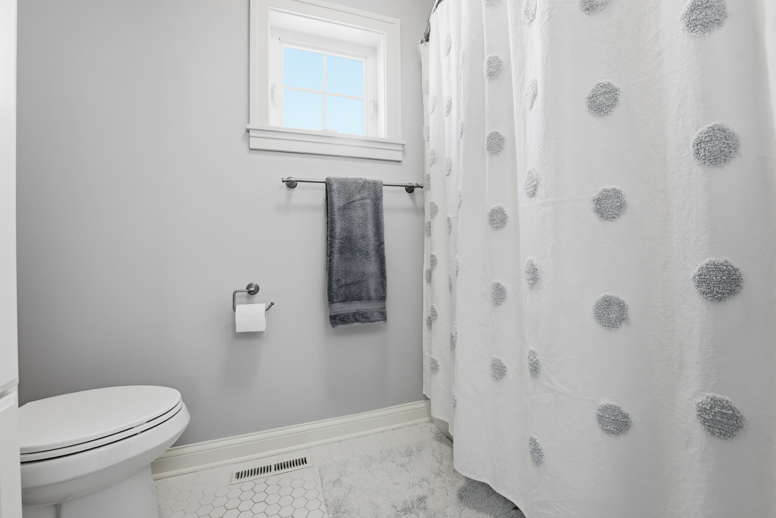 Real estate photography showcasing bathroom interior with patterned shower curtain and tile floor