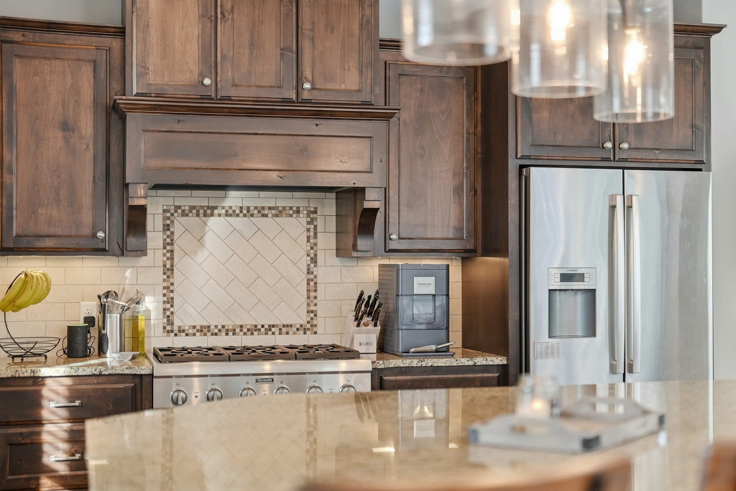 Real estate photography showcasing a modern kitchen with wood cabinetry and stainless steel appliances.