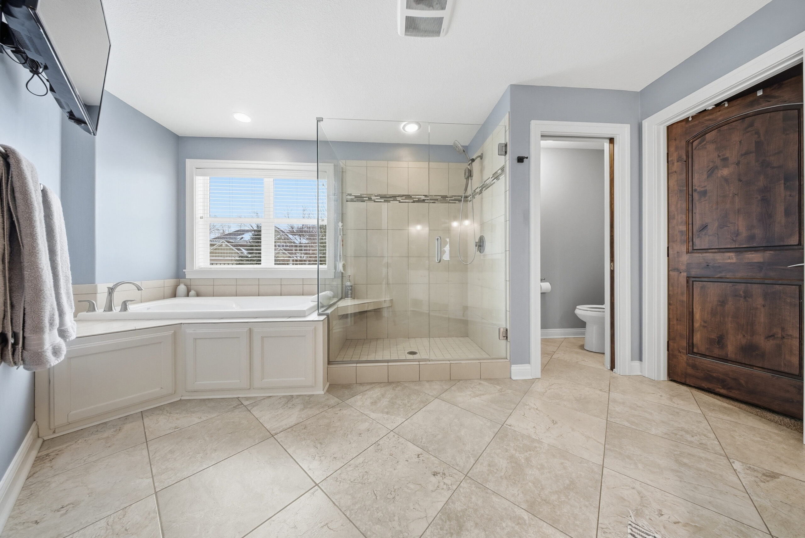 Luxury bathroom with glass shower and corner tub, real estate photography by Corridor Media.