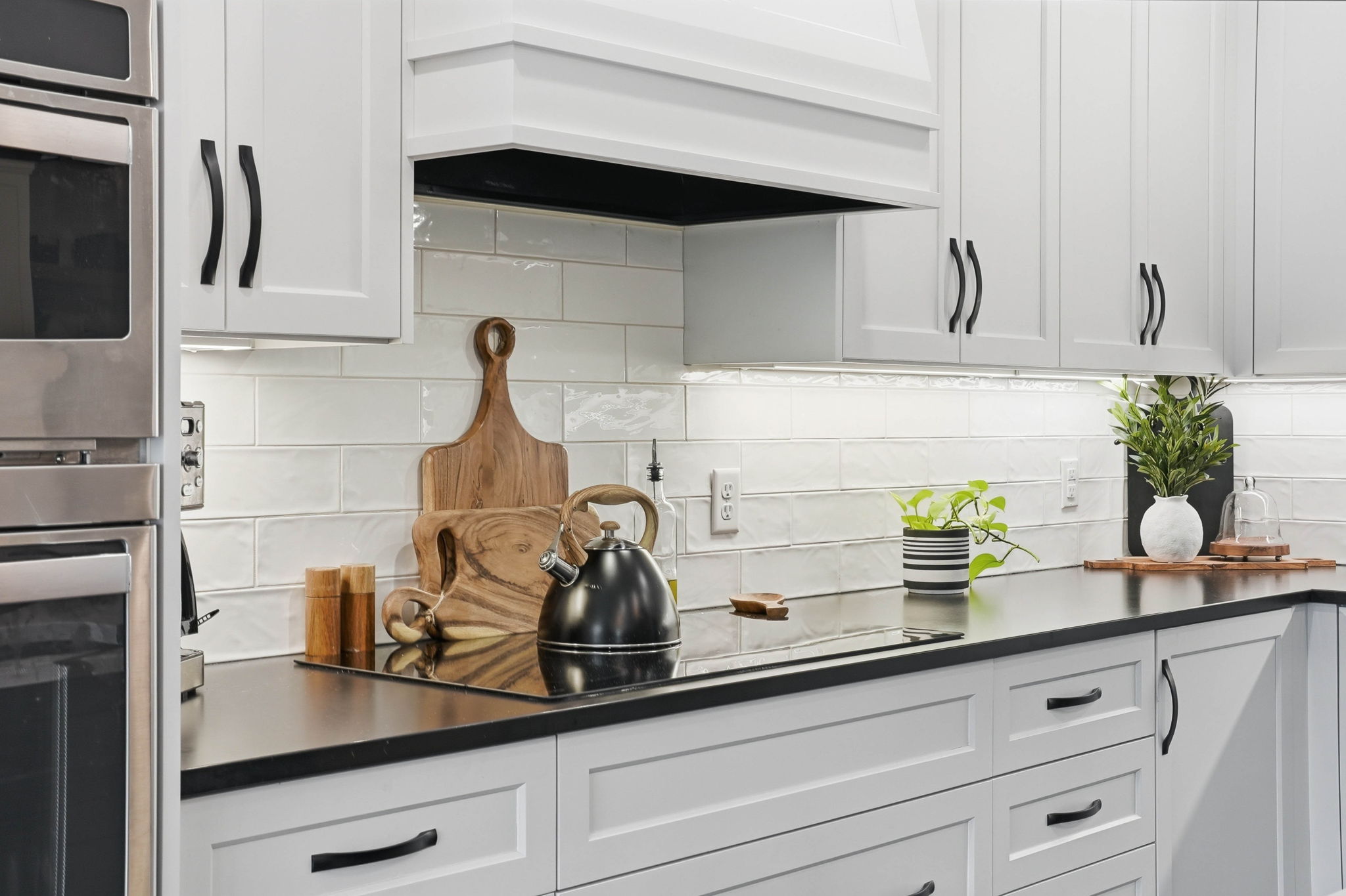 Remodeled kitchen with white cabinetry, black countertops, and stainless steel appliances in Arden Hills home.