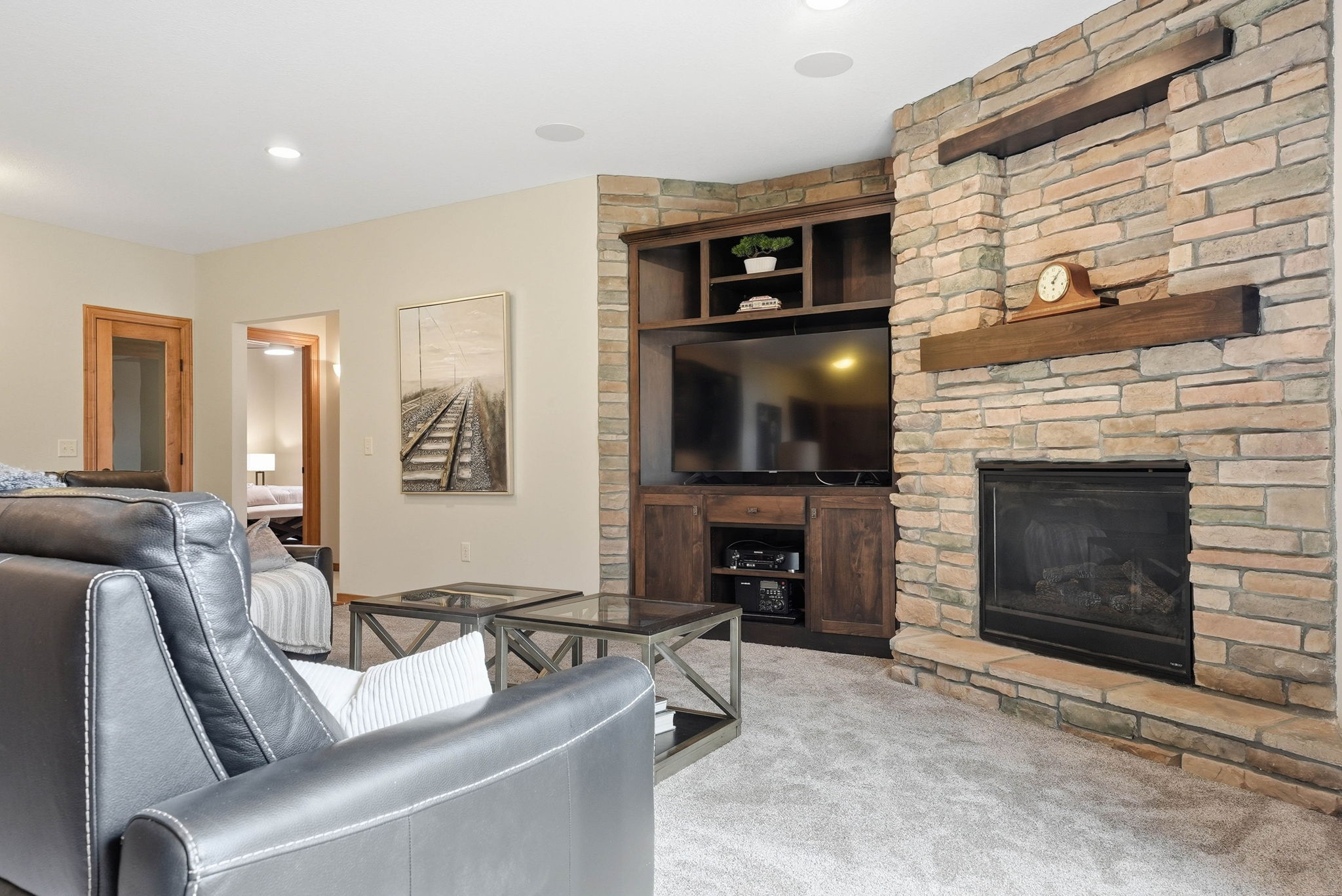 Stone fireplace with built-in entertainment center and modern living room furniture in Arden Hills home.