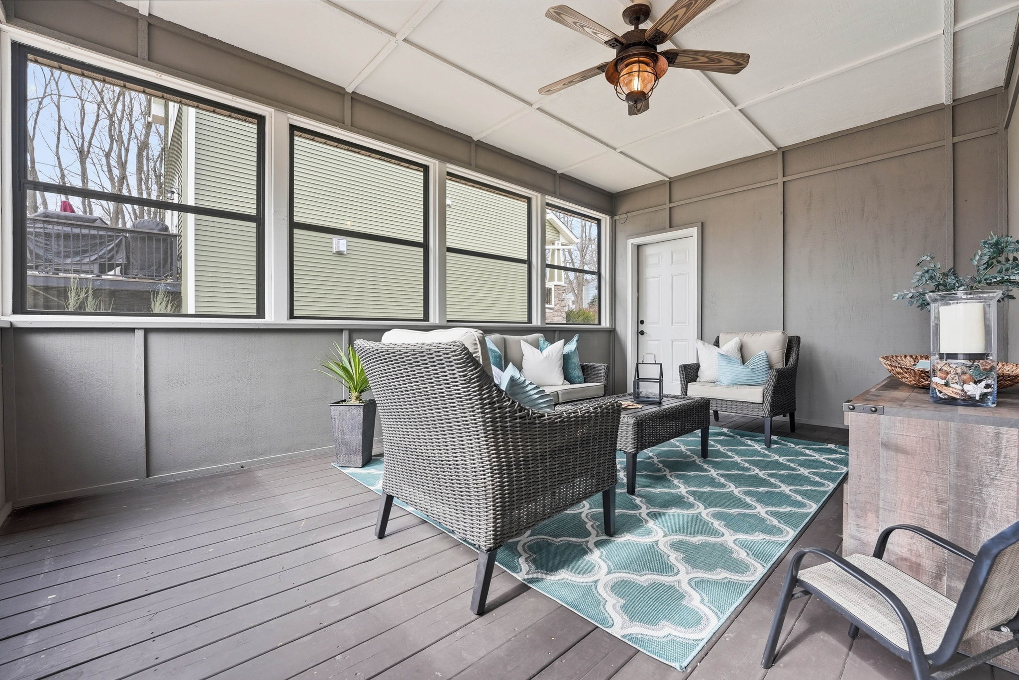 Three-season porch with seating and patterned rug in Arden Hills home.