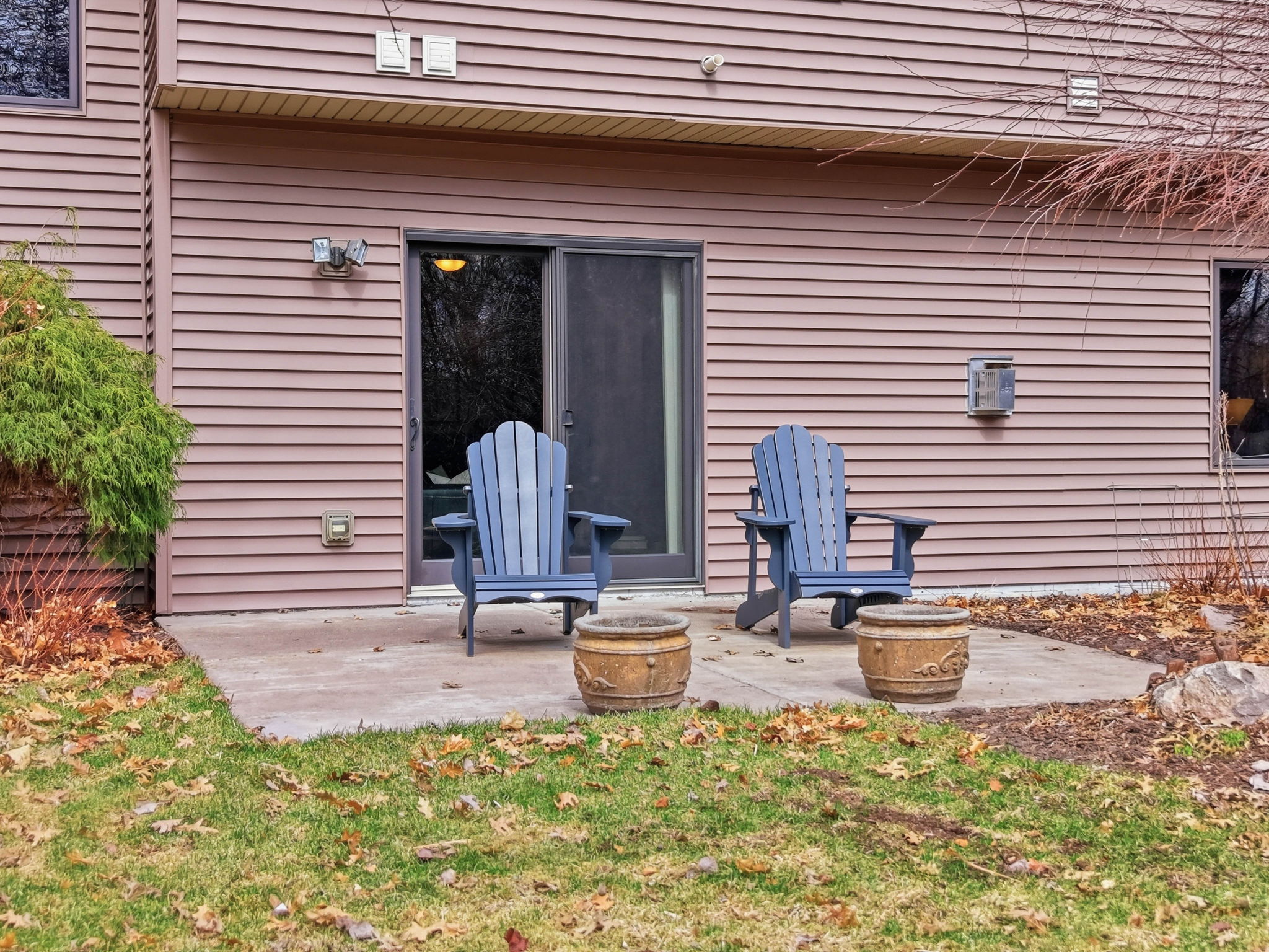 Walkout rambler exterior with patio, blue Adirondack chairs, and updated deck overlooking private backyard.