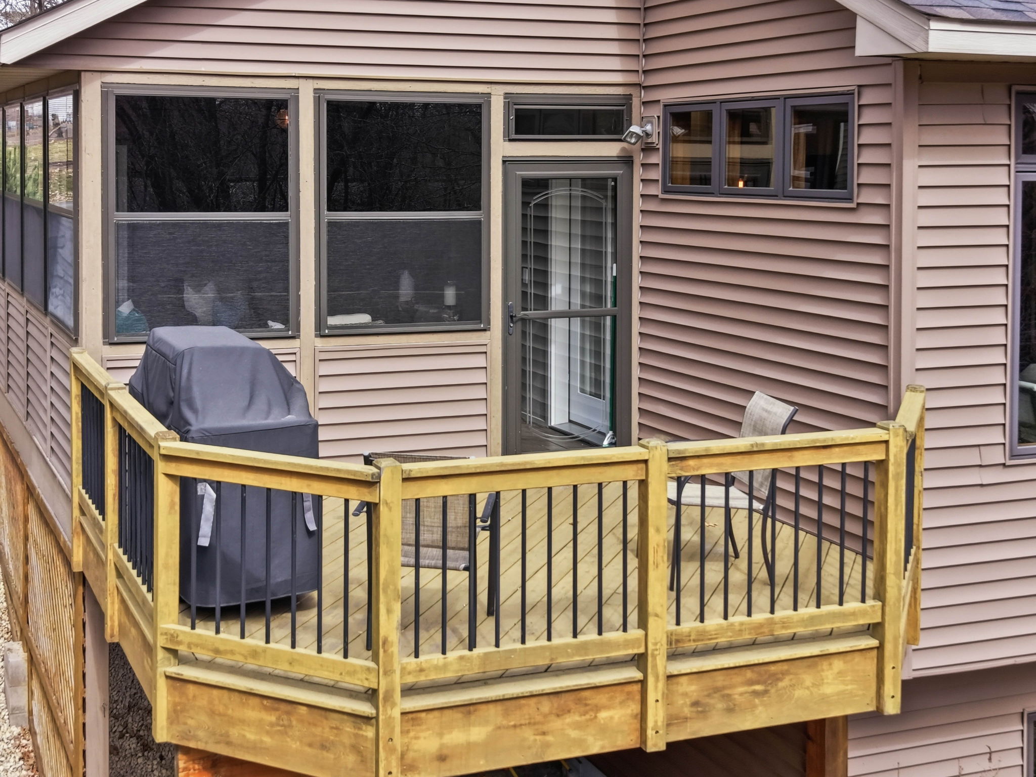Walkout rambler exterior with 3-season porch and deck overlooking private backyard.