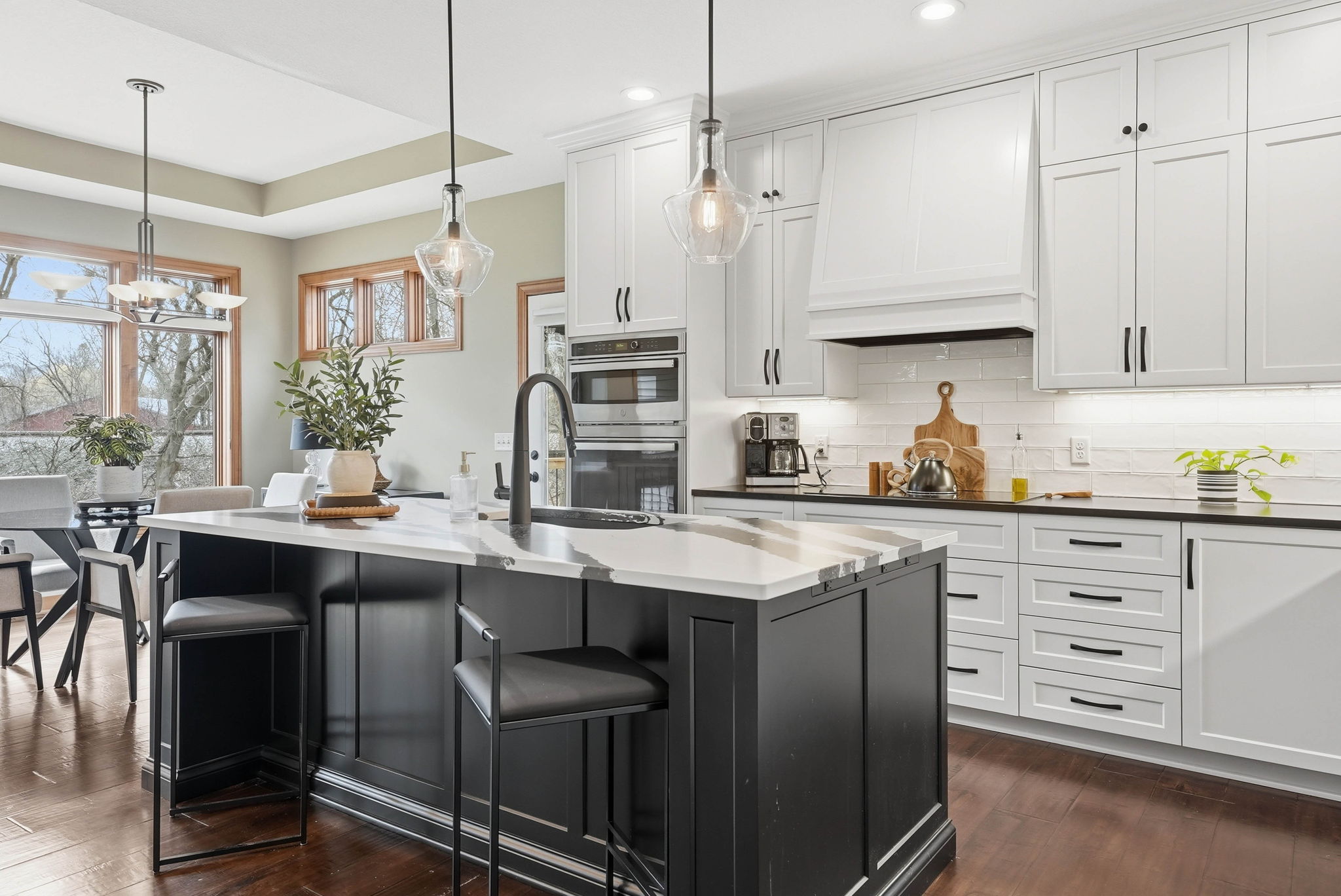 Remodeled kitchen with white cabinetry, black island, and stainless steel appliances in Arden Hills home.