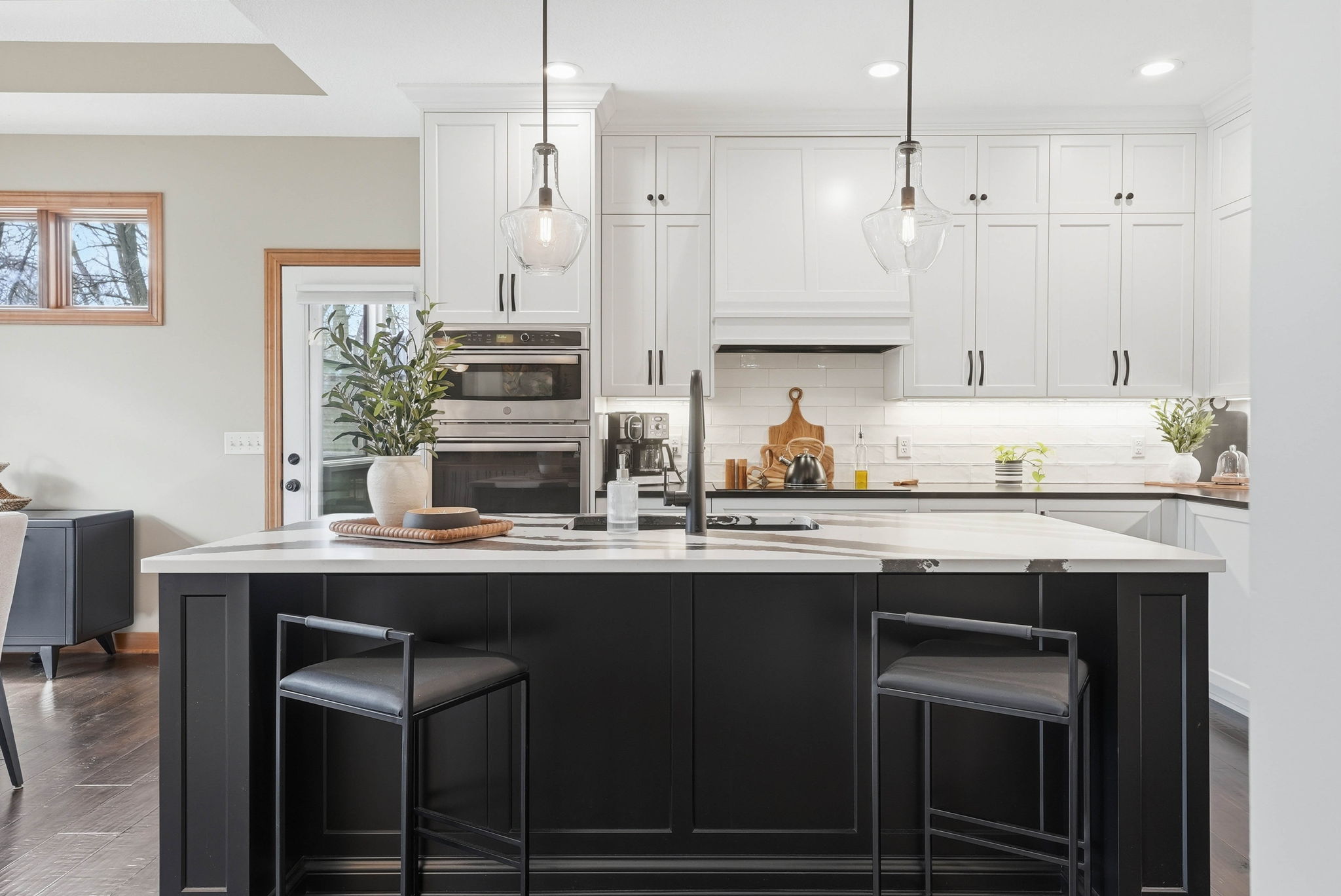 Remodeled kitchen with white cabinetry, black island, and modern pendant lighting in Arden Hills, MN home.